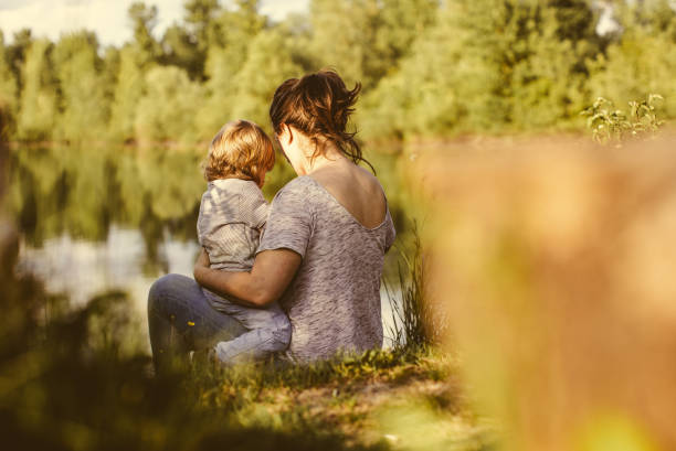 istock Mother With Son Sitting by the Lake 962366774