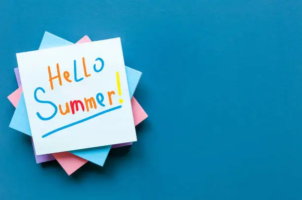 Photo of Hello Summer - inscription of many colored letters at notes on blue background. First summer day, Calendar concept. With copy space for text