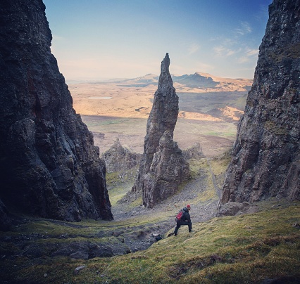 A Hiker stops on a steep path by the Needle Pinnicle at the Quirang on the Isle of Skye and contemplates the scene.