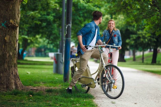 istock Happy Young Couple Riding Bicycles In Park 962379286