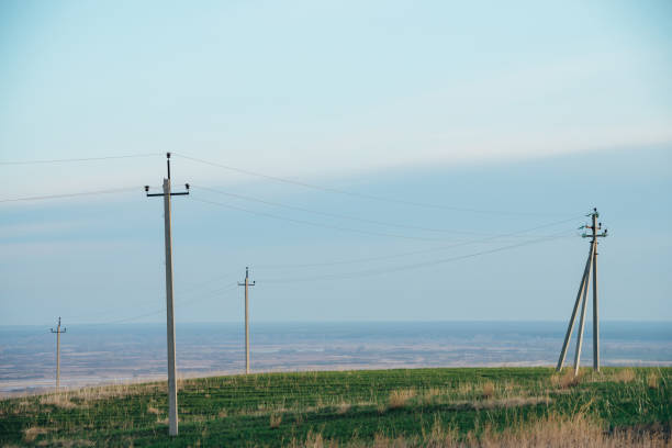 istock Atmospheric landscape with power lines in green field under blue sky. Background image of electric pillars with copy space. Wires of high voltage above ground. Electricity industry. 962388136