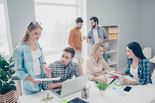 istock Confident, stylish, attractive colleagues in casual outfits having coffee break, talking, discussing, using smart phone, having mugs, cups with tea, partnership, relationship, community 962390502