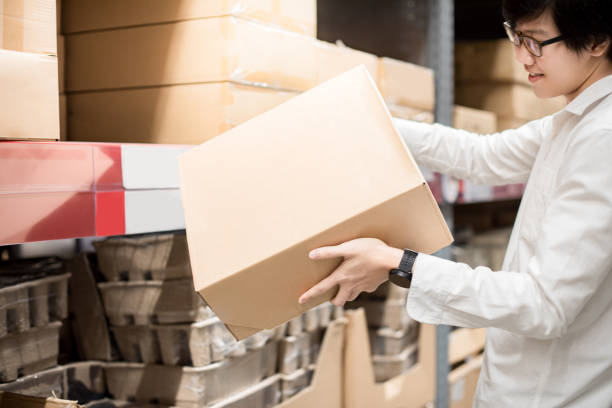 istock Young Asian man picking cardboard box from shelf in warehouse 962402958