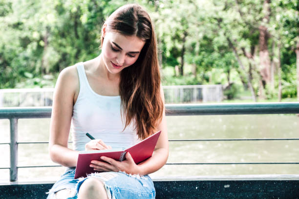 istock Woman with pen writing on a notebook sitting at home 962404370