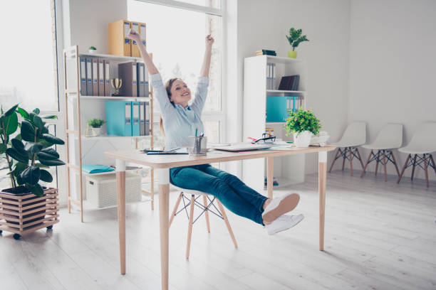 Full body portrait of nice, positive, charming, pretty woman celebrating completed project, finished working time with arms up, close eyes sitting in work place, station Full body portrait of nice, positive, charming, pretty woman celebrating completed project, finished working time with arms up, close eyes sitting in work place, station arms raised women business full length stock pictures, royalty-free photos & images