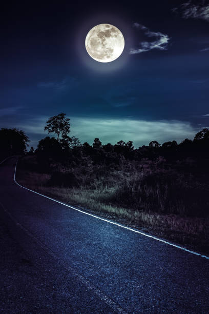 istock Dark sky with full moon and roadway through suburban zone. 962412776