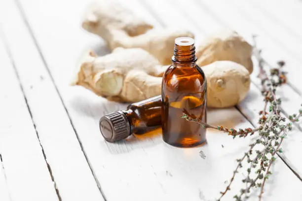 Ginger oil in a dark bottle on a wooden table.