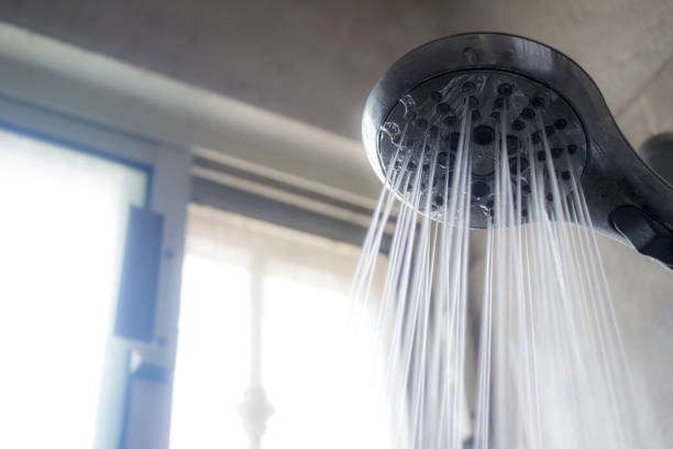 istock Close-up of a shower head and a water stream pouring from it in a spray pattern. 962429294
