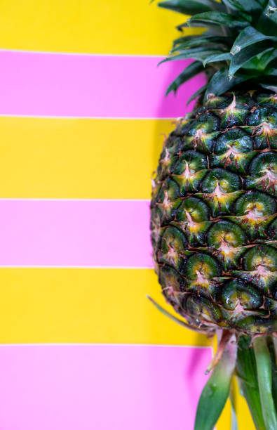 istock close up a half fresh ripe pineapple on stripes yellow and pink background, copy space, fancy minimal concept background 962436764