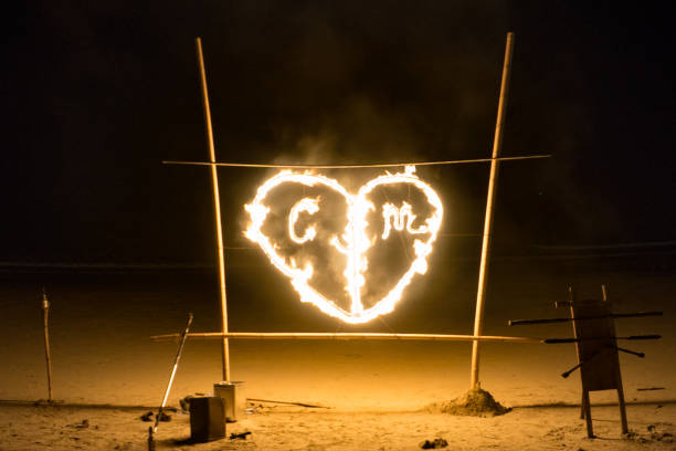 A tradition in Thailand at beach bars is to use fire to celebrate.  Here we see a heart shape on fire with letters within.  This is to commemorate the marriage of two people and start their wedding celebrations.  The location is the public beach on Ko Lanta, Krabi, Thailand.