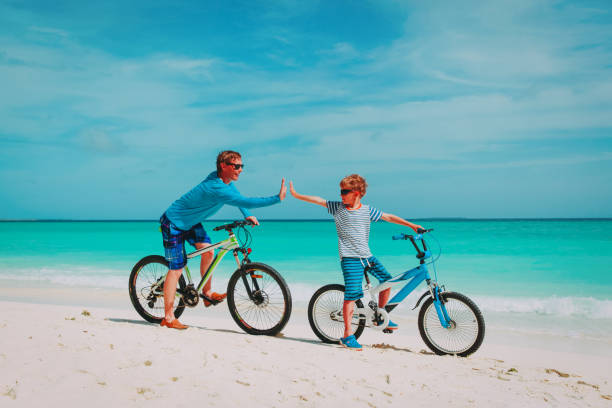 istock happy father and son biking on beach 962453370