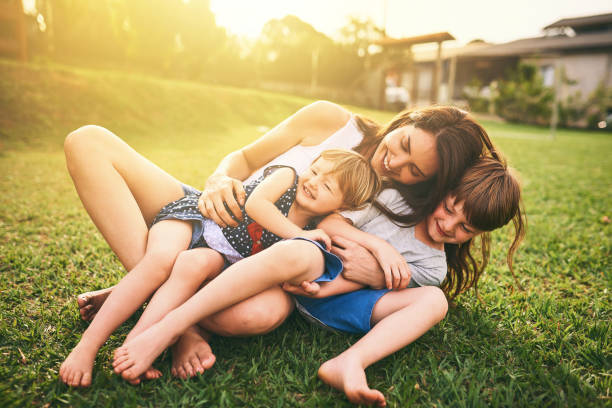 Your affection shapes their happiness for life Shot of a mother bonding with her two adorable little children outdoors happy sibling day stock pictures, royalty-free photos & images