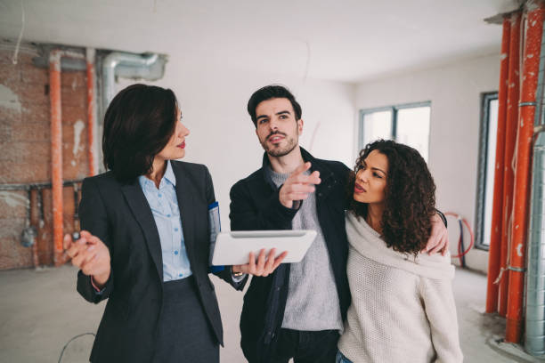istock Real estate agent with young couple viewing new house 962459618