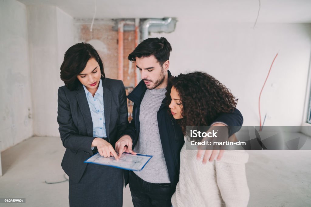 Real estate agent showing condo for sale to young couple Couple with real estate agent visiting property for viewing Real Estate Agent Stock Photo