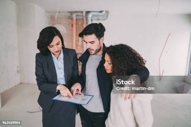 Real Estate Agent Showing Condo For Sale To Young Couple Stock Photo - Download Image Now