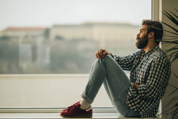 istock Young thoughtful man relaxing by the window at home. 962461416