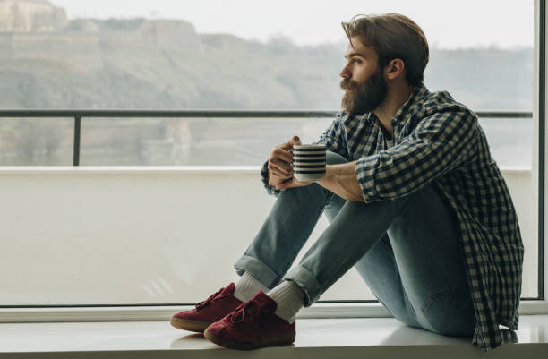 istock Serious man relaxing by the window during his coffee time. 962463734