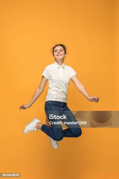 Freedom In Moving Pretty Young Woman Jumping Against Orange Background Stock Photo - Download Image Now