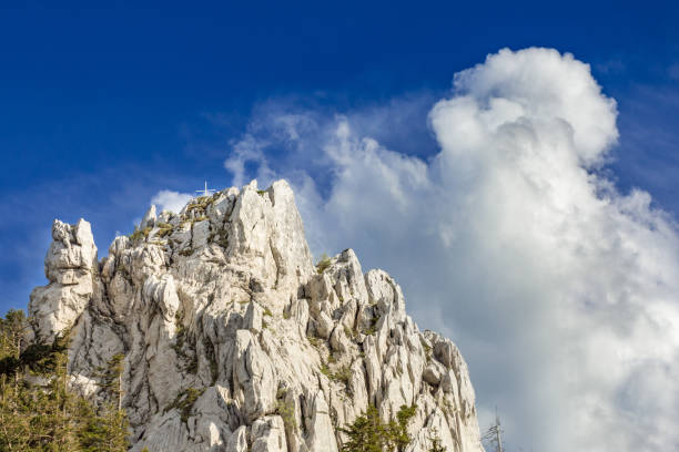 istock Clouds building up behind the mountain peak marked  with summit cross 962470142