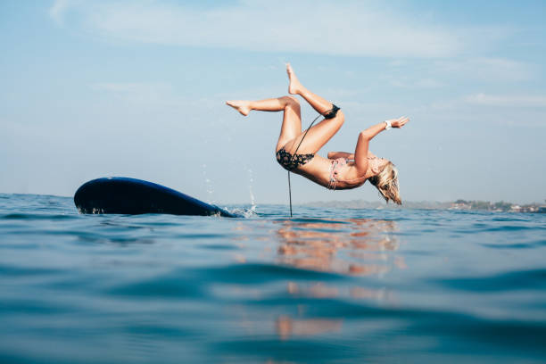 istock side view of woman falling off surfboard into water 962472654
