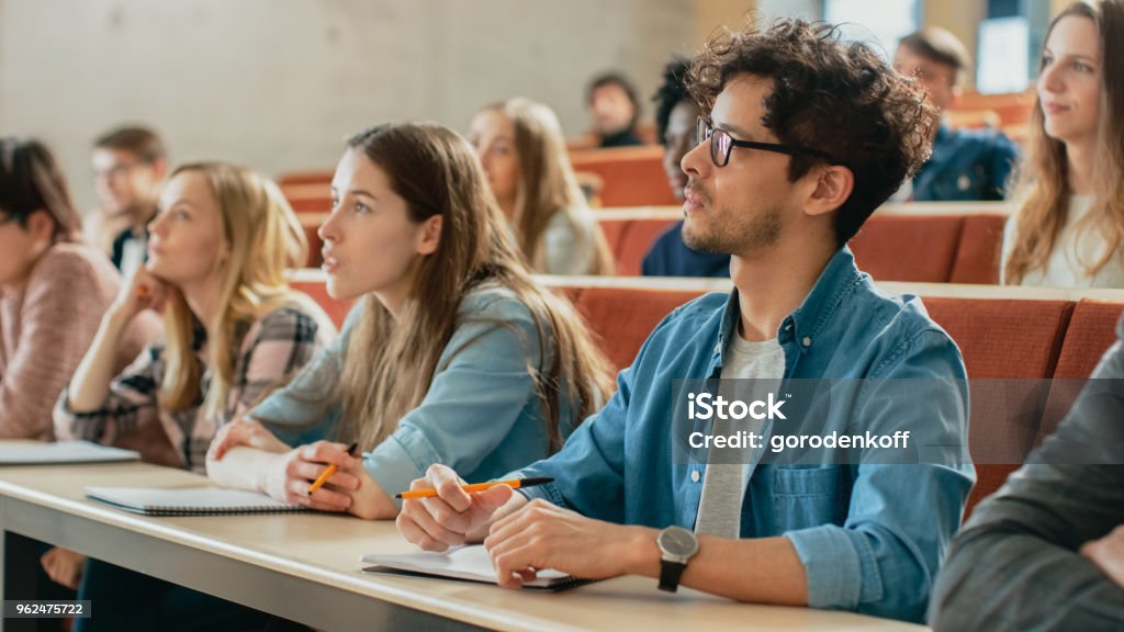 Dans la salle de classe Multi ethnique étudiants écouter un conférencier et l’écriture dans les ordinateurs portables. Les jeunes intelligente étude au Collège. - Photo de Université libre de droits