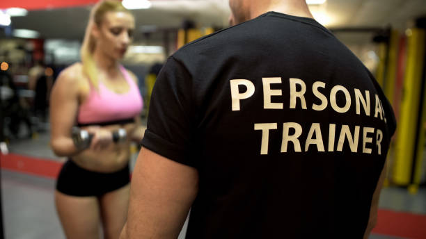 istock Personal trainer instructing attractive girl how to do dumbbell lifts properly 962476408