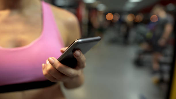 istock Woman scrolling pages on her mobile phone, having break from exercising in gym 962476448