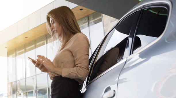 istock Nice business woman calling client on smartphone, standing near automobile 962477370