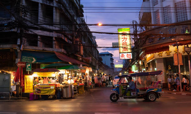 tuk tuk and shops on yaowarat road with its busy traffic, neon signs. chinatown with notable chinese buildings, restaurants and street food stalls. chinatown, bangkok, thailand - 05/05/18 - jinrikisha thailand tuk transportation imagens e fotografias de stock