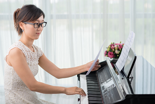 Creative young Asian woman learning new melody