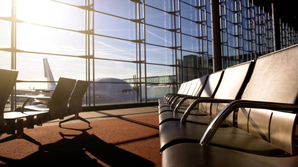 istock Waiting room in airport terminal with empty seats under morning sunrays, trip 962477570