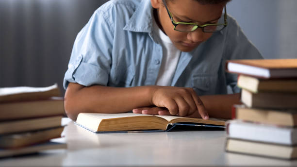 istock Smart Afro-American boy reading books, bookworm kid, little nerd, education 962478058