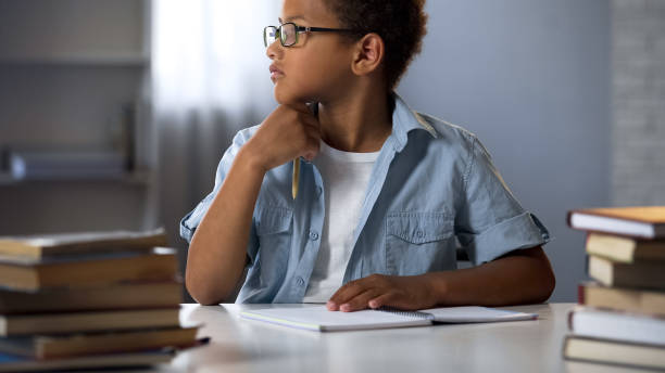 istock Schoolboy holding pen thinking on literature essay, doing homework, education 962478104