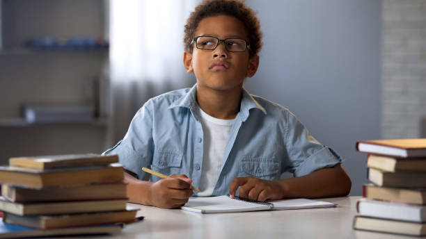 istock Afro-American boy thinking on school essay, smart kid doing homework, education 962478116