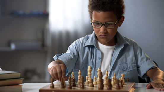 Smart boy playing chess carefully thinking through each move, logical game