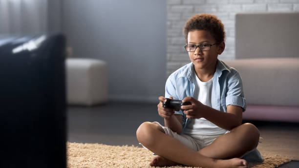 istock Afro-American schoolboy spending his free time playing games on console, leisure 962478240