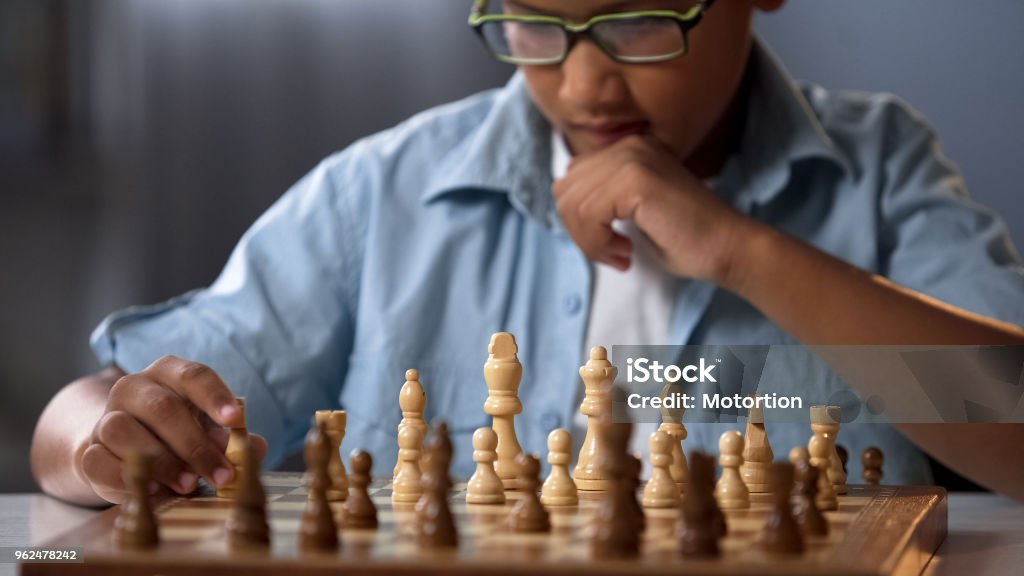 African kid moving knight piece during chess tournament, game strategy analysis Chess Stock Photo