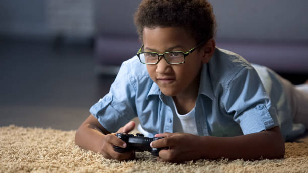 istock Afro-American boy absorbedly playing on new video game console, home activity 962478268