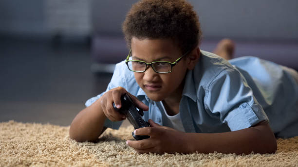 istock Small boy playing video game lying on floor at home, online competition, rest 962478274