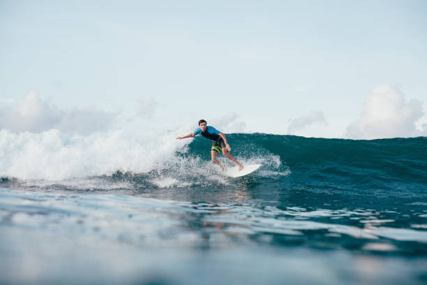 istock young man in wetsuit riding waves on surfboard on sunny day 962478530