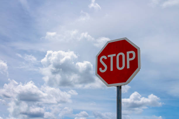 istock Red stop sign and blue sky with white clouds in background 962487182
