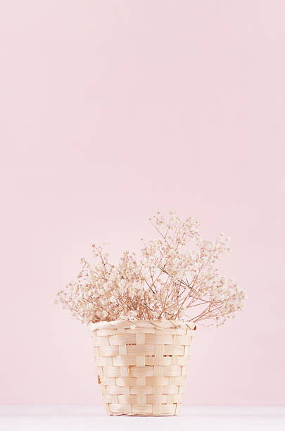 istock Modern soft pink pastel home interior with natural dried white flowers in rustic basket on soft light wooden background. 962491962