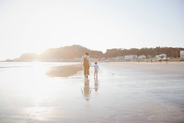 istock Mother and son walking on the beach together 962496408