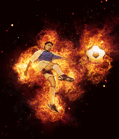 Soccer player kicking ball surrounded by fire and flames