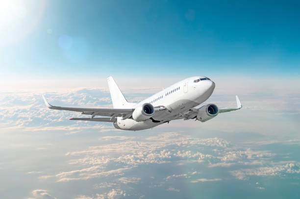 istock Passenger white airplane flies in a blue sky with a bright sun. 962511828