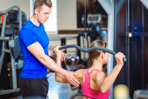 gut aussehend persönlicher trainer führt eine schöne frau in einem modernen fitnessclub - tattoo men human arm shoulder stock-fotos und bilder