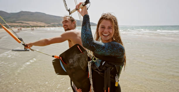 Kitesurfing Cheerful young man and woman getting ready for kitesurfing. kite sailing stock pictures, royalty-free photos & images