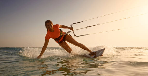 Woman doing kitesurfing Portrait of smiling young woman doing kitesurfing in sea at sunset. kite sailing stock pictures, royalty-free photos & images