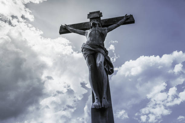 istock Antique crucifix, lit by the sun, against the sky with clouds 962527658
