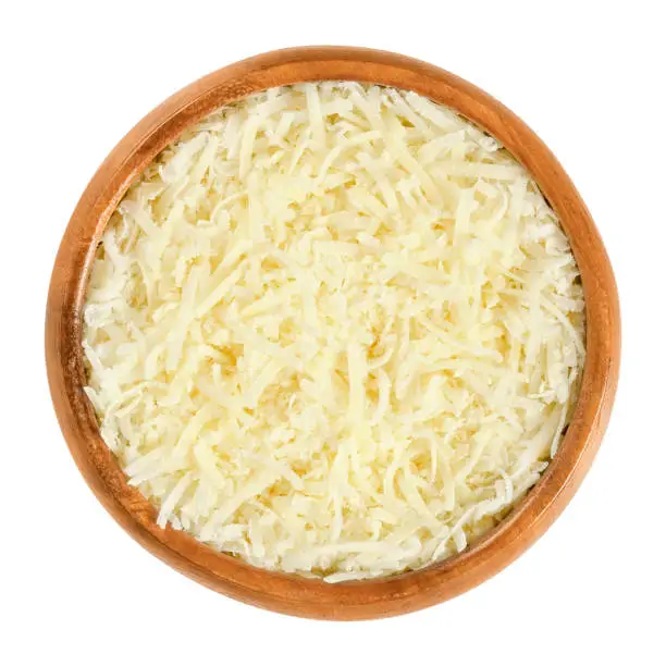 Grated Parmesan cheese in wooden bowl. Parmigiano-Reggiano. Italian hard, granular cheese, of slightly yellow color, made of unpasteurized cow milk. Macro food photo, closeup, from above, over white.